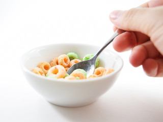 Spoon scooping colored o-shaped sugary cereal