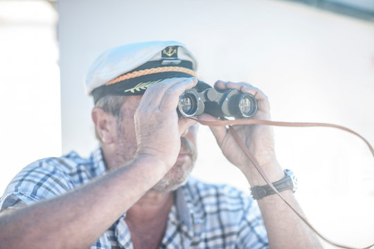 Boat captain looking through binoculars on boat, Cape Town, South Africa