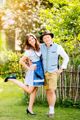 Fototapeta premium Couple in traditional bavarian clothes standing in the garden