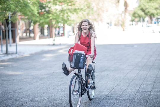 Happy businesswoman freewheeling on bicycle in city