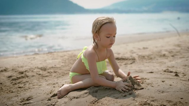 Adorable little girl playing on white sand beach