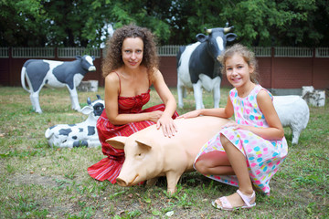 Mother and daughter (with model releases) near garden sculptures pig and three cows in the territory of College of Hospitality and Management in Moscow