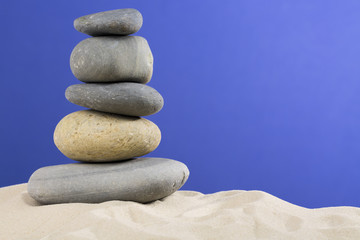 some stones on each other with nice sand against blue background
