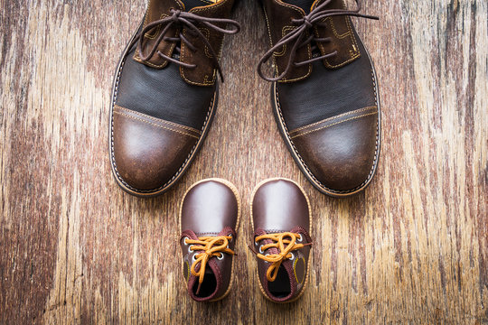 Father and son brown shoes on wooden background, flat lay, top view 