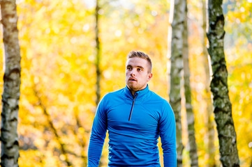 Young handsome hipster runner outside in sunny autumn nature