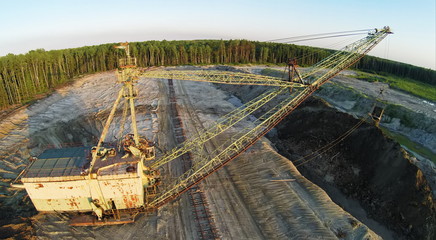 Excavator works at sandpit during sunset. Aerial view. (Photo with noise from action camera)