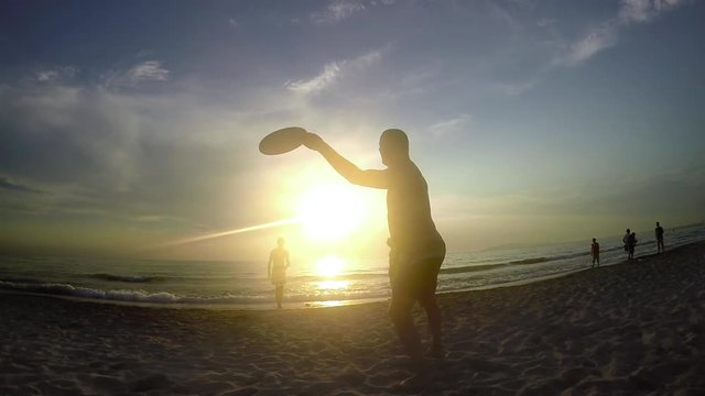 Summer Beach Fun Playing Frisbee at Sunset