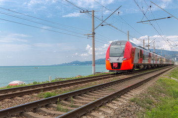 Fototapeta na wymiar red train rides on rails along the seashore