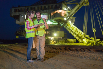 Worker shows documents to her colleague on background of career stacker