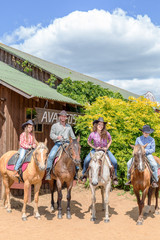 cowboy family of four on horses on background of wooden building
