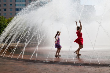 Mother and her daughter are dancing into the fountain.