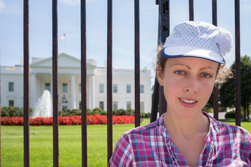 Woman smiles near lattice of White House in Washington DC.