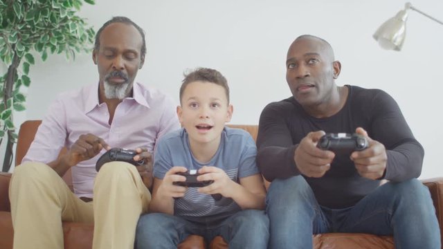  3 Male generations of happy family playing video games together at home
