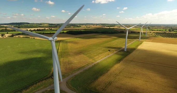 Aerial view looking across four wind turbines in motion on a summers day