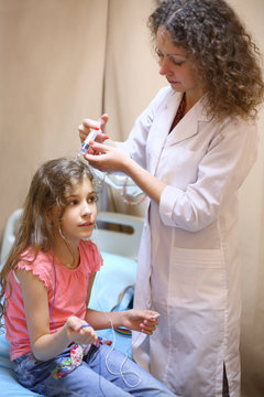 Medical worker will put electrode gel on the girls head for electroencephalography