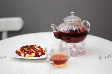 Stylish kettle with tea and sweet dessert