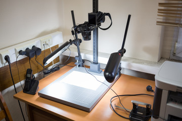 Camera for photocopying is standing on the table at office.