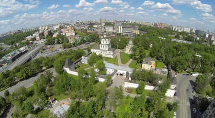 Fototapeta na wymiar Spaso-Andronikov monastery against city with traffic on river embankment and railroad at sunny day. Aerial view.