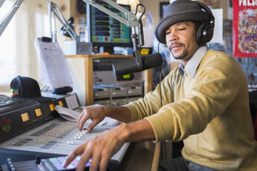 Mixed race disc jockey using control panel in studio