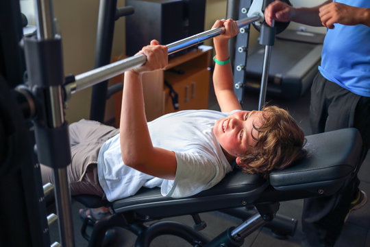 Teenage Boy Lifts A Barbell In A Gym