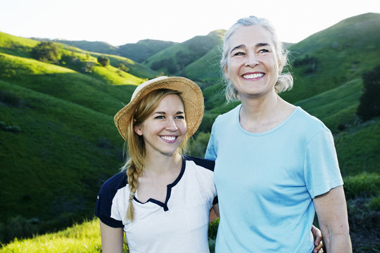 Caucasian mother and daughter smiling on rural hilltop