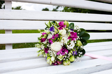 Fototapeta na wymiar Beautiful bridal bouquet of flowers on wooden bench 