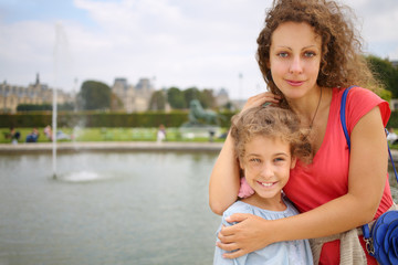Portrait of a beautiful woman and girl in a park near the fountain