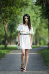 Full length portrait of a beautiful young caucasian woman in white dress with open shoulders, clean skin, long hair and casual makeup