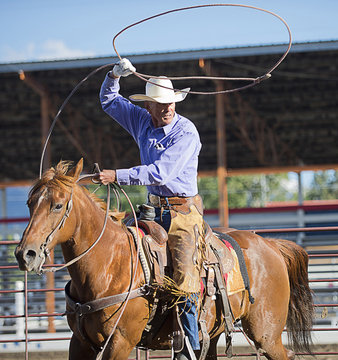 Older Caucasian cowboy throwing lasso at rodeo
