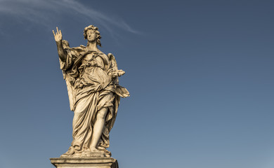 Fototapeta na wymiar A large, stone statue of an angel, against a deep blue summer sky