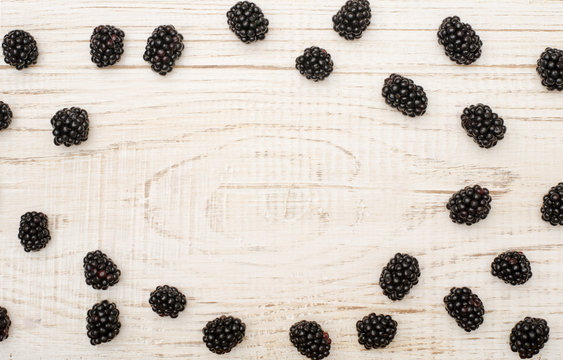 Blackberries on a wooden light background as a frame