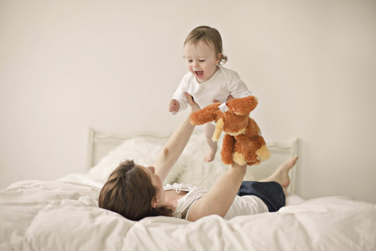 Caucasian mother playing with baby on bed