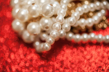 Jewelry background with white pearls on a red glitter