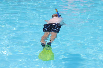 A young boy snorkeling in a swimming pool while on vacation, 2016