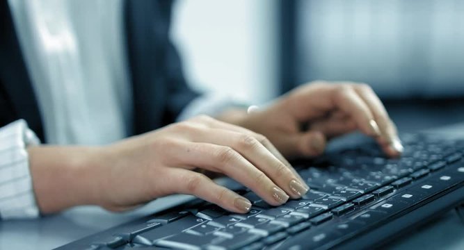 4K: Eine Geschäftsfrau schreibt schnell auf einer Tastatur. Es sind nur die Tastatur und ihre Hände in Nahaufnahme zu sehen. Der Bildstil ist bläulich.