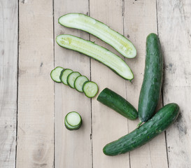 Fresh and ripped cucumbers decorated with rosemary on wooden des