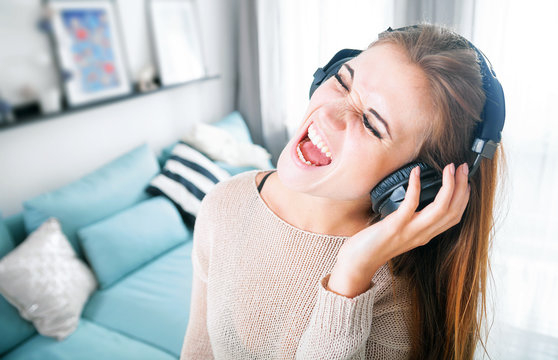 Woman with headphones singing and listening to music at home