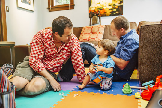 Gay fathers and baby son playing in living room