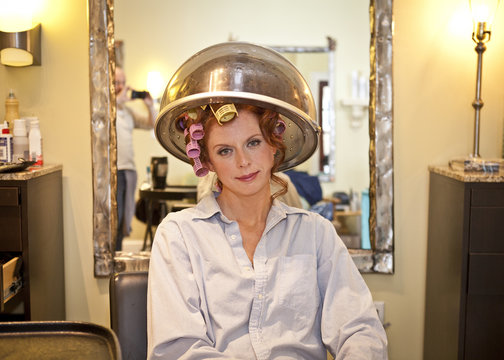 Woman Sitting Under Hair Dryer In Salon