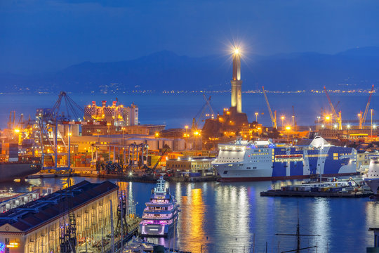 Historical Lanterna old Lighthouse, container and passenger terminals in seaport of Genoa on Mediterranean Sea, at night, Italy.