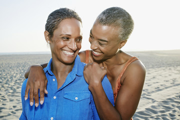 Older Black women hugging on beach