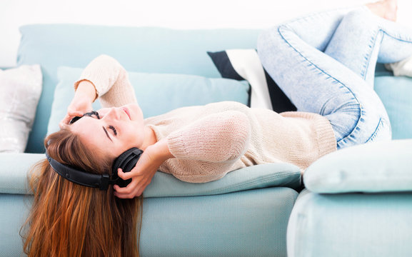 Woman with headphones lying and listening to music at home