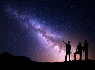 Milky Way with silhouette of a standing young man pointing finger in night starry sky and his...