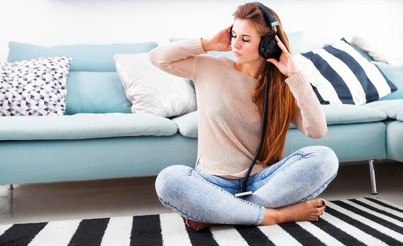 Woman with headphones listening to music at home