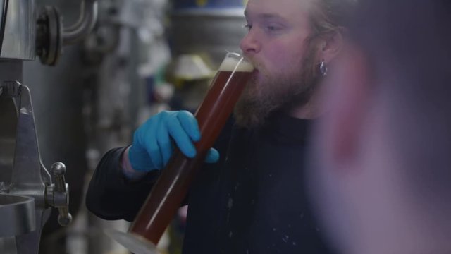  Worker in a brewery tasting beer & checking quality of the finished product