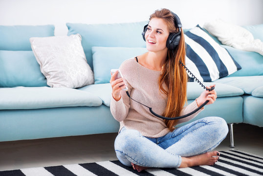 Woman with headphones listening to music at home