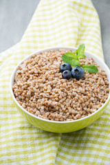 Buckwheat porridge in a bowl with mint leaves and blueberries.