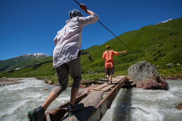 Tourists pass bridge across mountain river