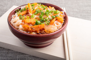 Asian food of rice noodles in a small brown wooden bowl