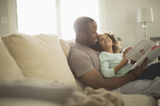 Father and daughter reading on sofa